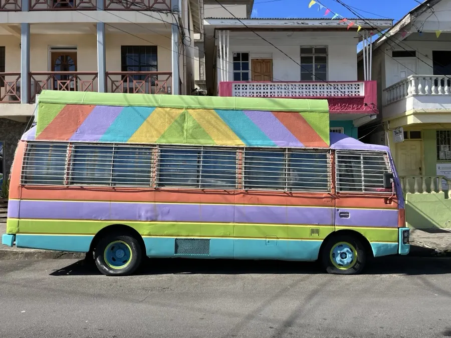 A rainbow-painted bus on a town street