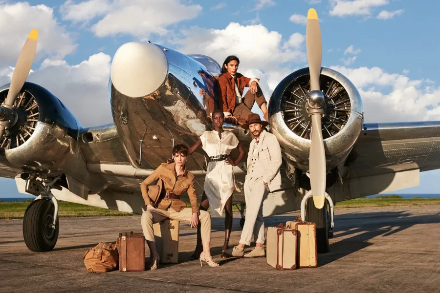 Group with suitcases beside a silver aircraft